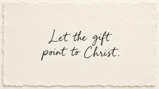Black handwriting on ivory handmade paper reading "Let the gift point to Christ."