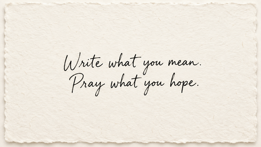 Black handwriting on ivory handmade paper reading "Write what you mean. Pray what you hope."