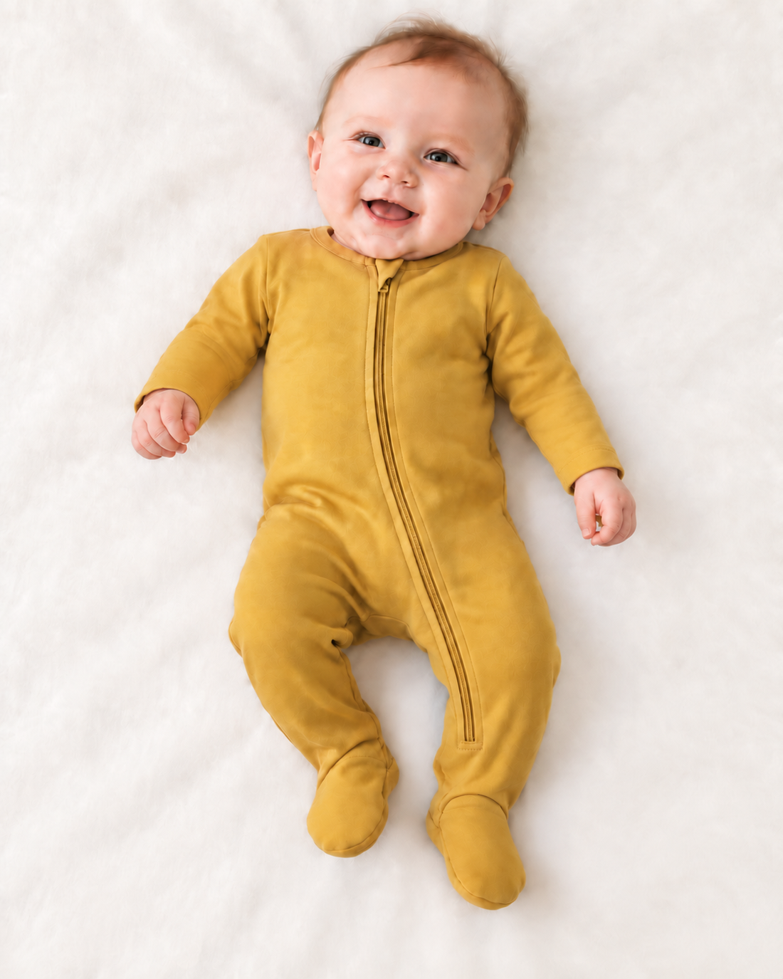 Baby wearing the Mustard organic zip footie with hands uncovered