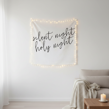Decorative tapestry with 'silent night holy night' text and string lights in a living room setting.