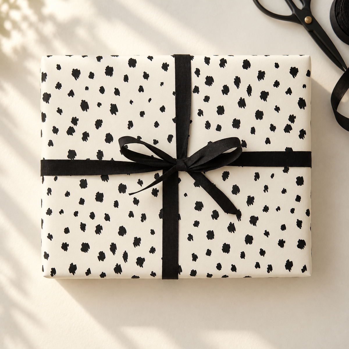 Black and off-white Dalmatian gift wrap styled with black ribbon.