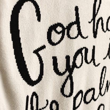 Natural ivory God Has You blanket close-up showing black hand-lettered artwork and fine knit texture.
