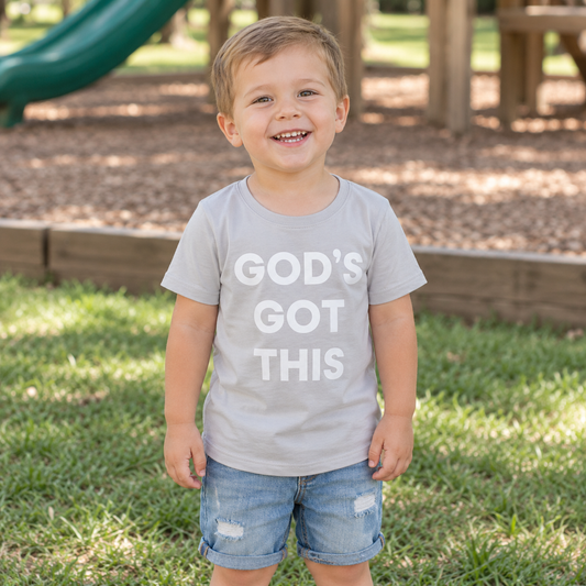 AI-styled child wearing the light gray God’s Got This scoop neck tee at a neighborhood playground