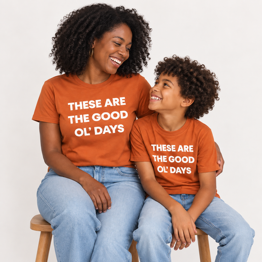 These Are the Good Ol’ Days Organic Unisex Tee | Sunburn worn by a mother alongside her child in the Sunburn kids tee — AI-generated studio image; each sold separately.