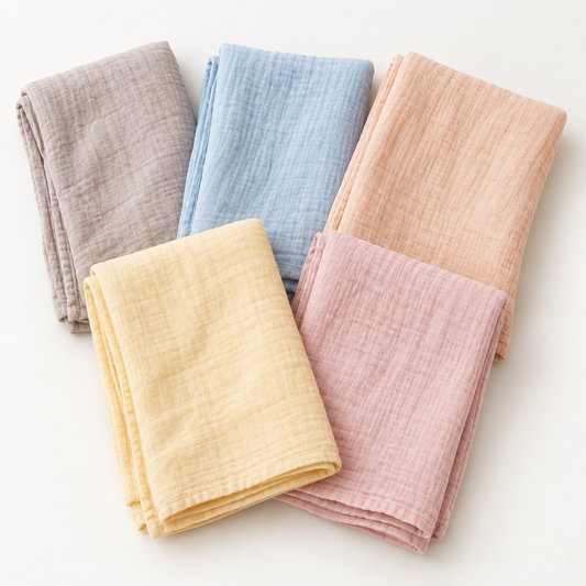 Five folded hand-dyed organic swaddle colors: pink, blue, yellow, peach and taupe. Swaddles sold individually.