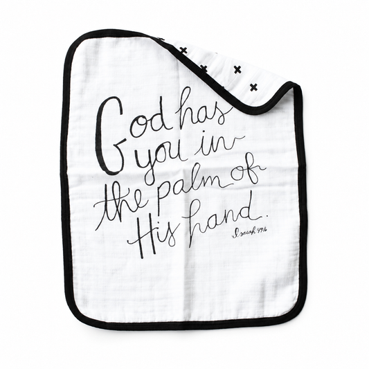 Isaiah 49:16 muslin burp cloth with 'God has you in the palm of His hand' lettering and a folded corner showing the Swiss Cross reverse on white.