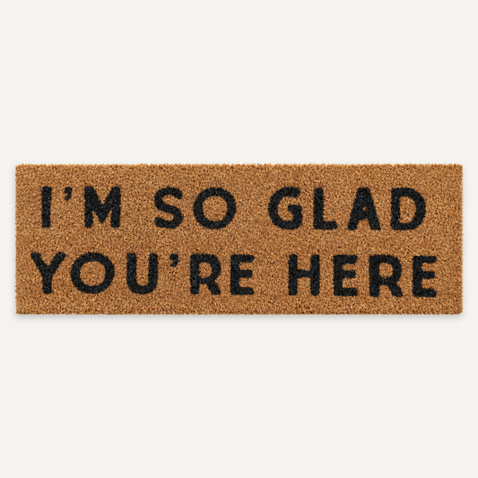 I'm So Glad You're Here | XL Doormat shown alone on a warm off-white studio background.