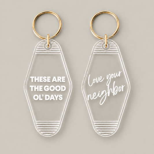 These Are the Good Ol’ Days and Love Your Neighbor clear vintage keychains at matching scale on warm gray. Choose one message; sold individually.