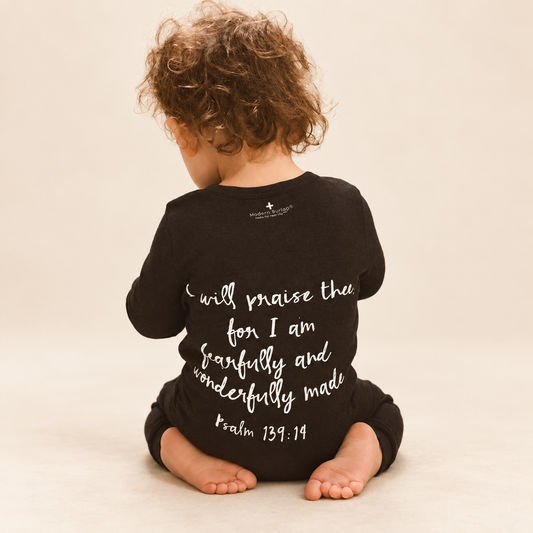 Psalm 139:14 Organic Button Coverall worn by a child against a warm ivory background; AI-enhanced from original product photography.