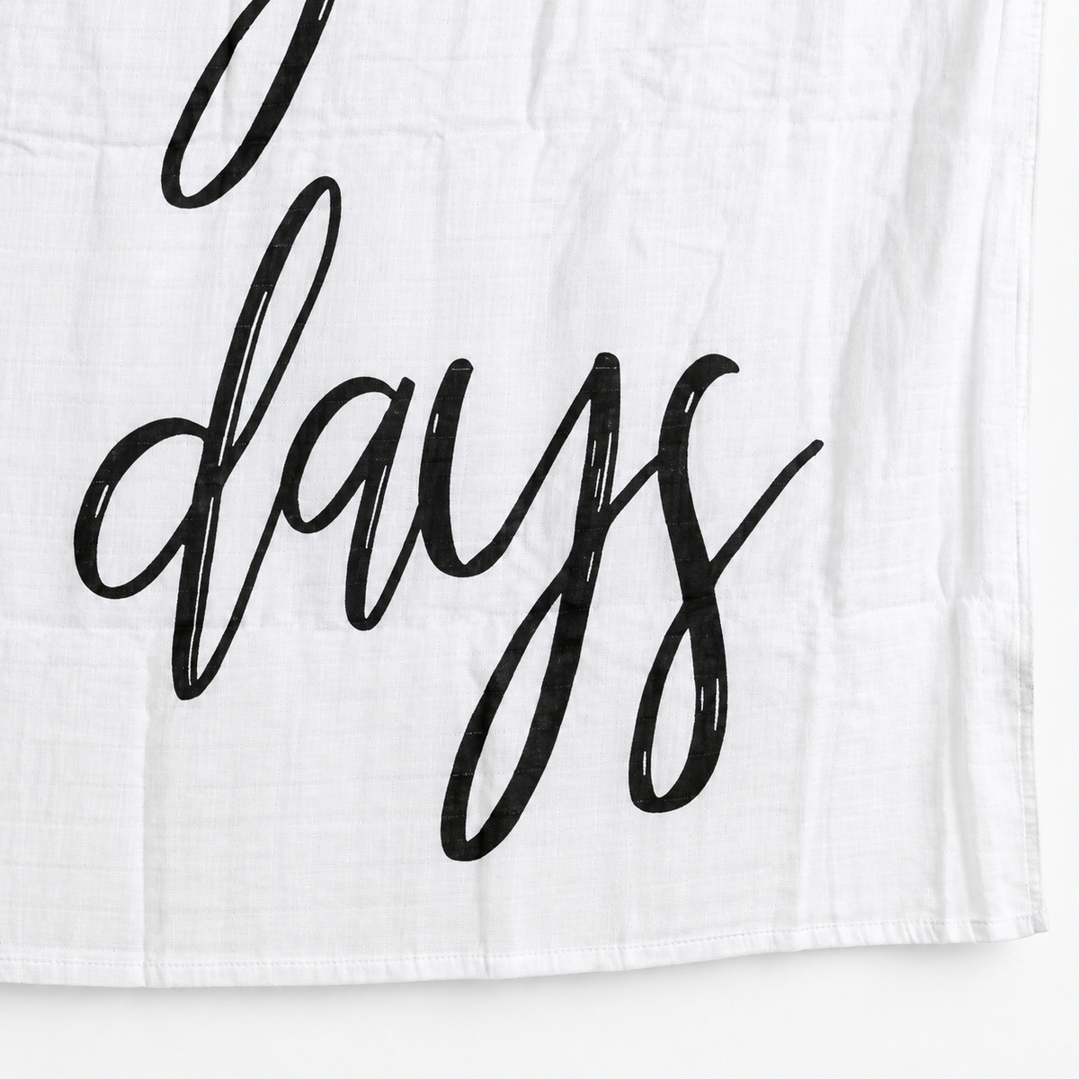 Close view of black calligraphy, white cotton muslin and the hem of These Are the Good Ol' Days swaddle.