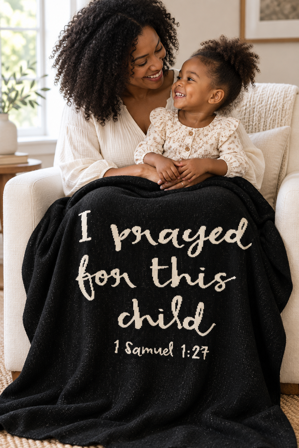 Mother and toddler sharing the Black I Prayed for This Child knit blanket in an armchair.