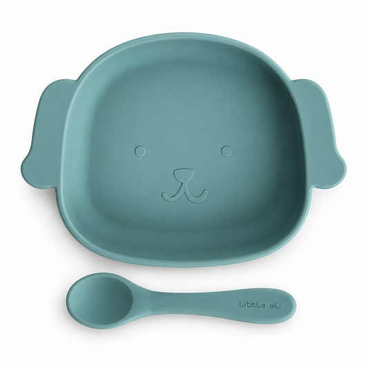 Little Eli Light Fern puppy silicone plate and matching spoon on white; storage bag included but not shown.