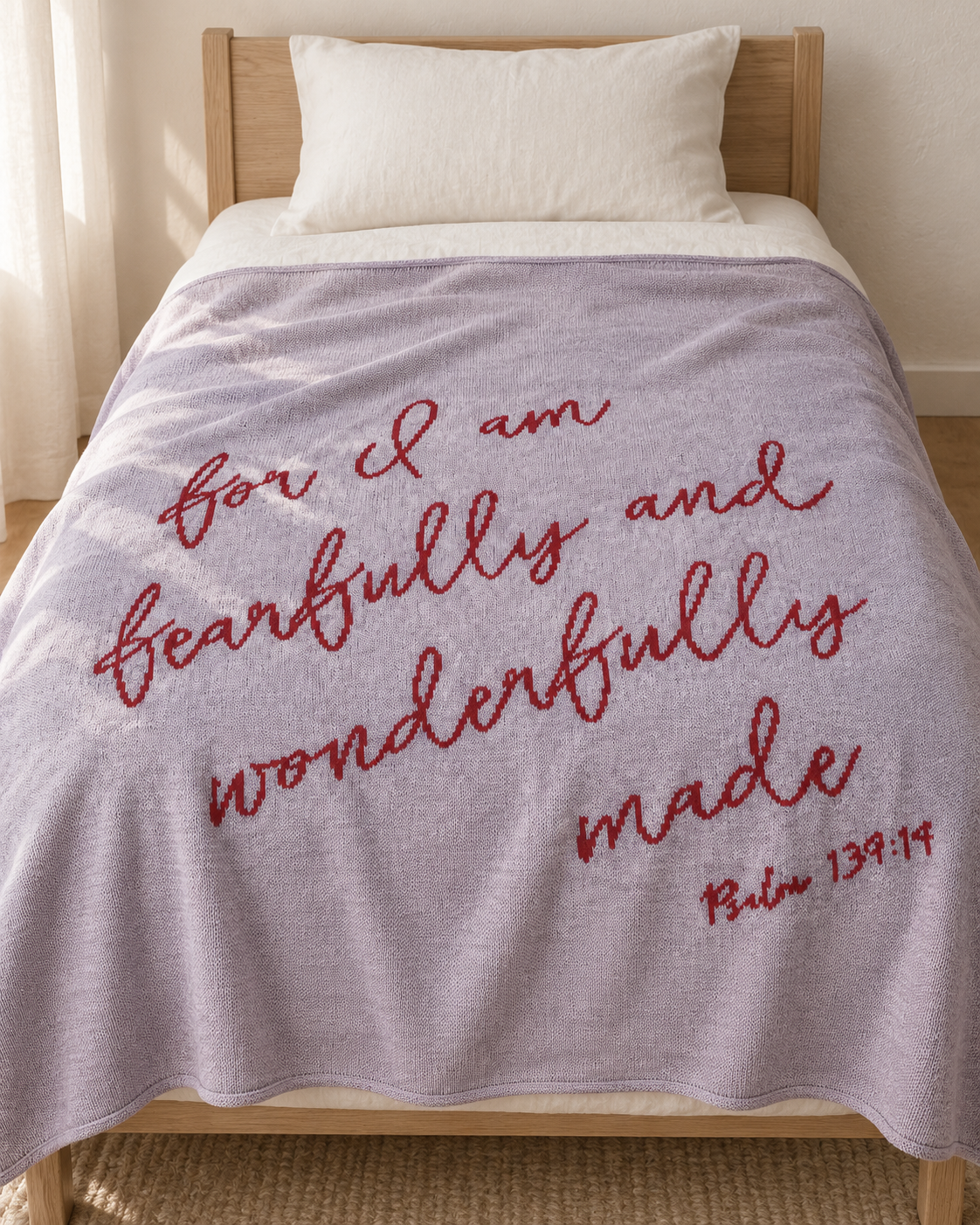 Lipstick Fearfully and Wonderfully Made recycled cotton blanket styled across a twin bed with white linen and a natural wood frame.
