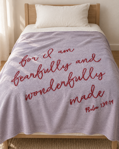 Lipstick Fearfully and Wonderfully Made recycled cotton blanket styled across a twin bed with white linen and a natural wood frame.