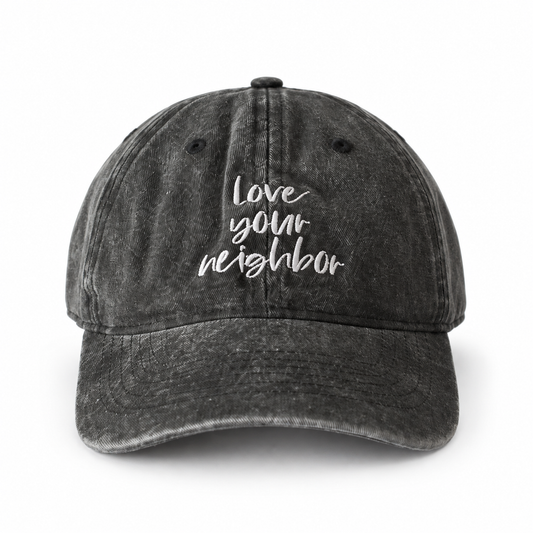 Washed black child-size Love Your Neighbor cap with white script embroidery.