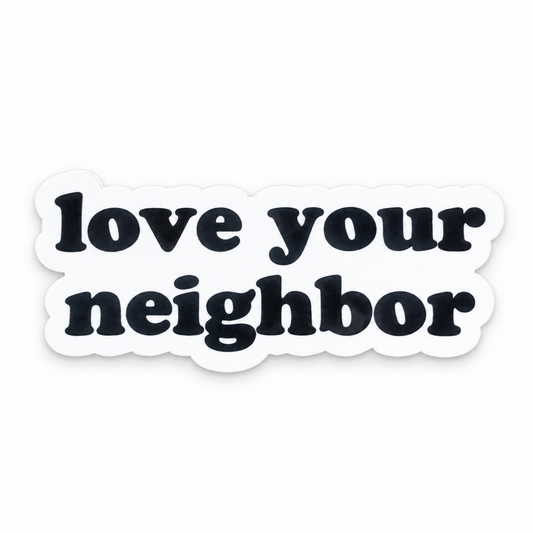 Love your neighbor magnet, black original lettering and white die-cut border, front studio view.