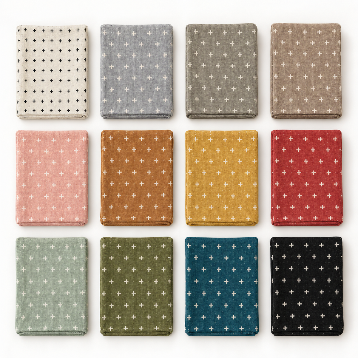 Twelve Mini Swiss Cross blanket colors folded at a consistent scale: Natural, Aluminum, Topo, Taupe, Cameo Pink, Caramel, Straw, Rust Red, Sky Green, Kaki Green, Teal and Black. Each blanket sold separately.