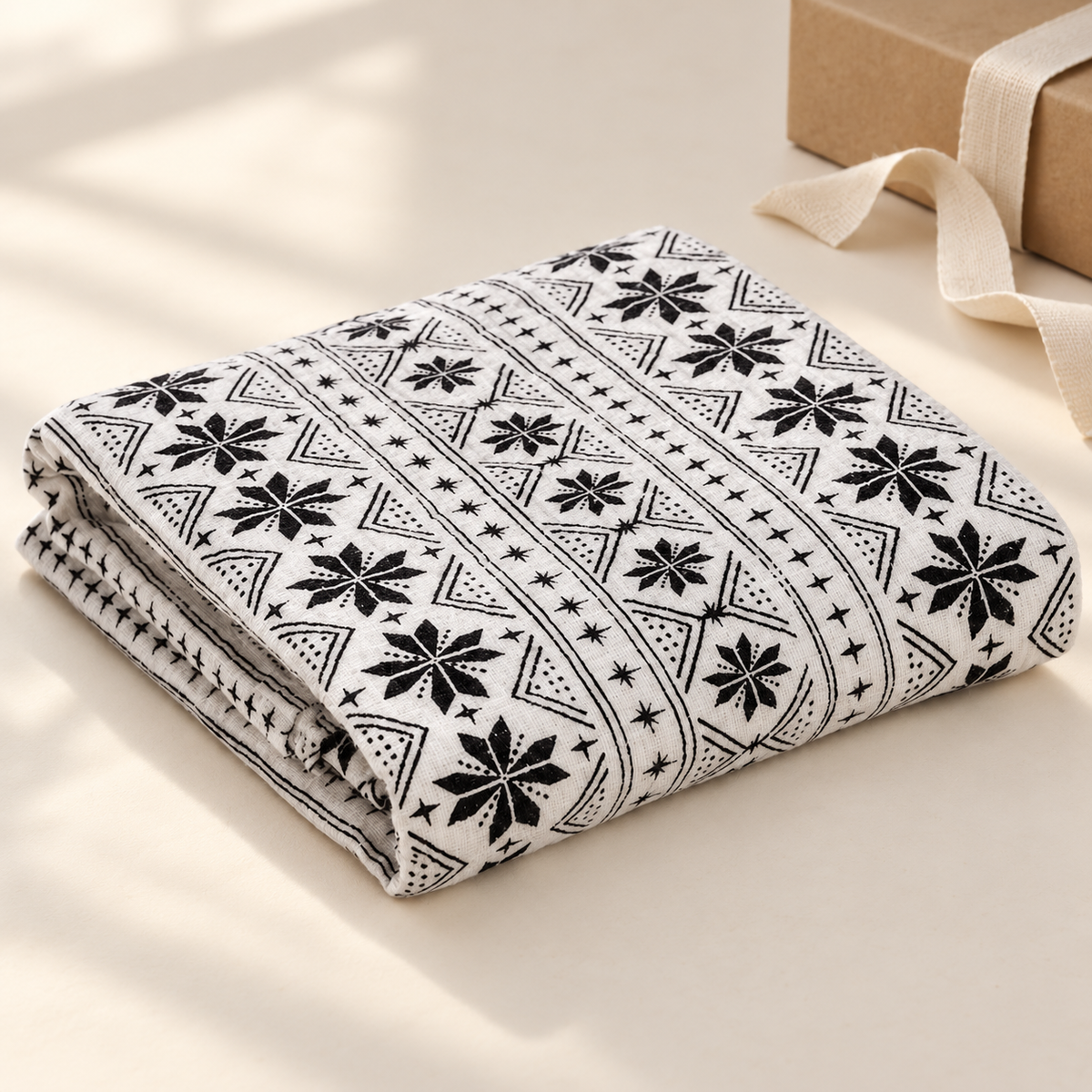 AI-styled gift view of the folded Nordic Winter organic cotton muslin swaddle; gift box and ribbon are styling props, not included.