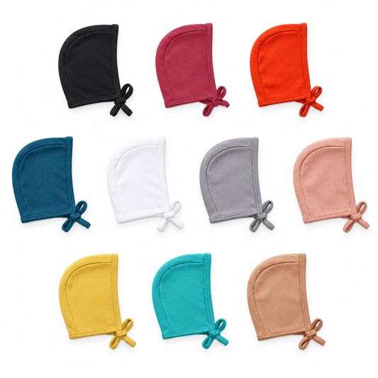 Ten organic baby bonnet colors at matching scale: Black, Maroon, Cherry Tomato, Sailor Blue, White, Neutral Gray, Blooming Dahlia, Mustard, Arcadia and Ginger.