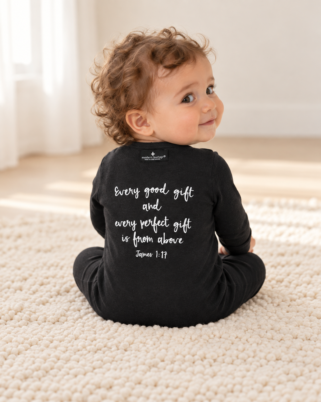 Baby showing the back design of James 1:17 Organic Zip Footie; AI-styled product image.