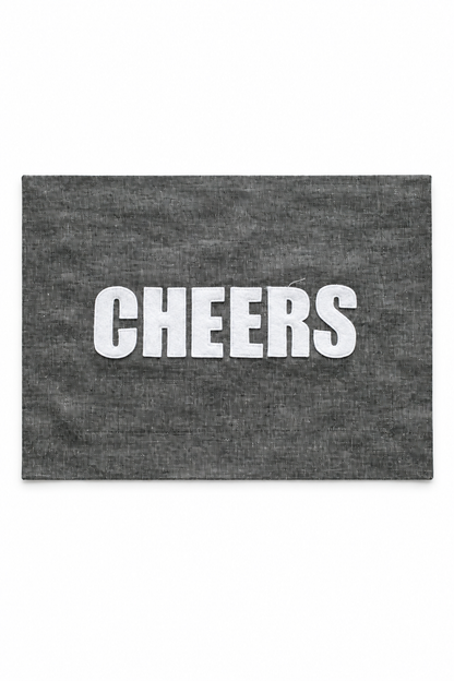 Graphite linen placemat with ivory Cheers lettering. One placemat.