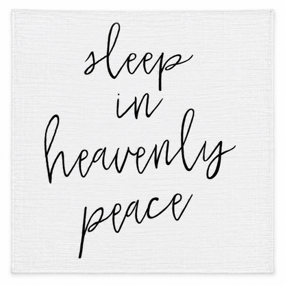 Sleep in Heavenly Peace organic muslin swaddle laid flat, showing the full black handwritten design on white fabric.