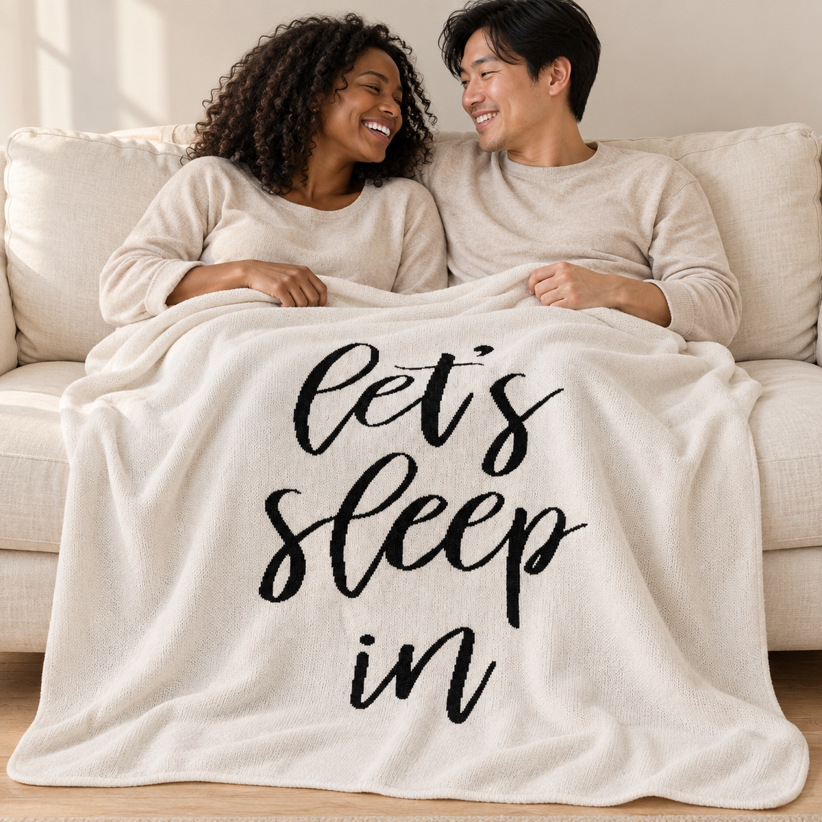 Couple sharing a Natural Let's Sleep In knit throw on an ivory sofa.