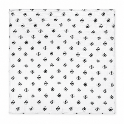 Snowflakes organic cotton muslin swaddle laid fully open, showing the square shape, black snowflake print and stitched edges on a white studio background.