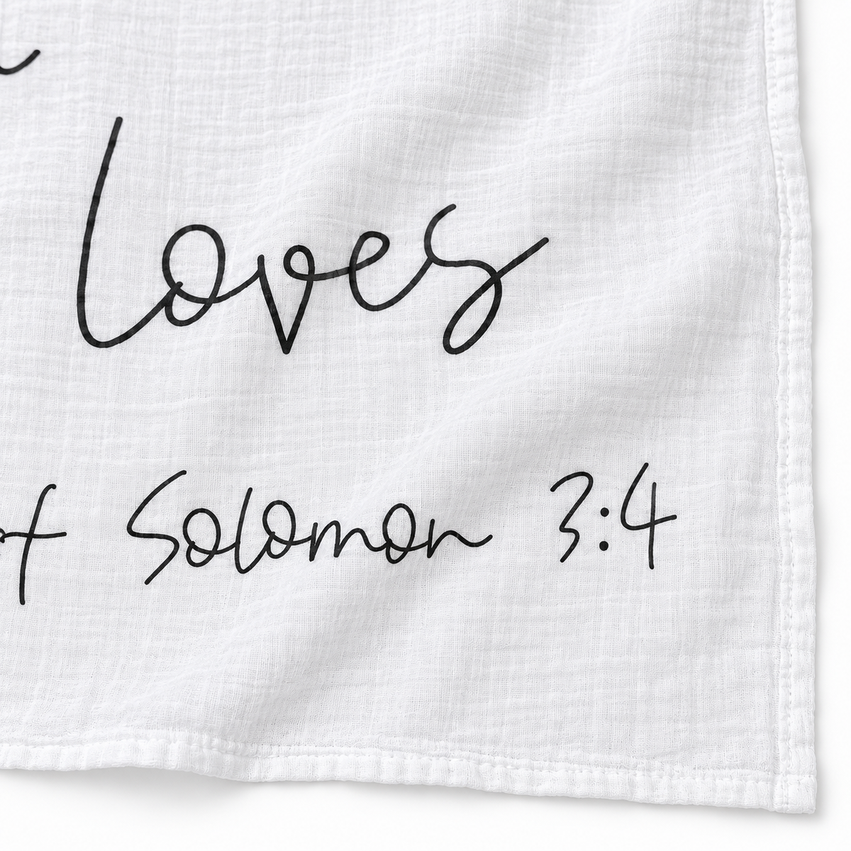 Close-up of the Song of Solomon 3:4 swaddle showing white muslin texture, stitched hem and black handwritten lettering.
