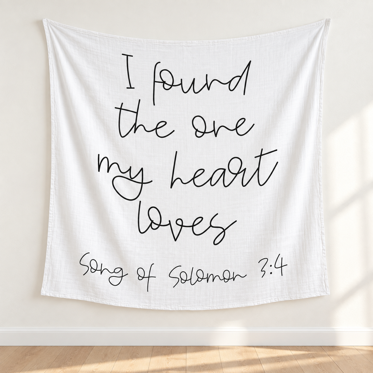 Song of Solomon 3:4 white muslin swaddle displayed as a textile wall hanging above pale oak flooring.