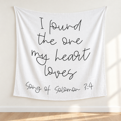 Song of Solomon 3:4 white muslin swaddle displayed as a textile wall hanging above pale oak flooring.