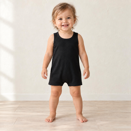 Toddler standing in the Black organic tank romper