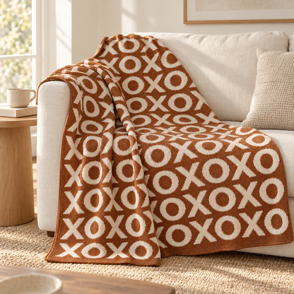 Caramel XO knit throw draped over an ivory sofa, showing the pattern and natural fabric drape.