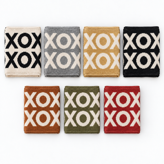 Seven folded XO knit blanket colors: Natural, Aluminum, Straw, Black, Caramel, Kaki Green and Rust Red. Each blanket sold separately.