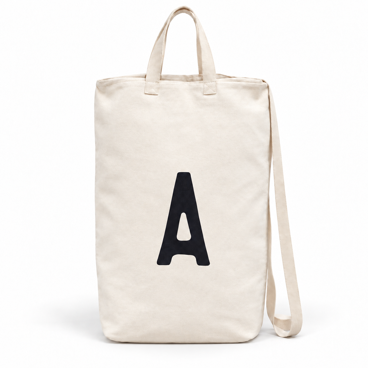 A initial ivory cotton canvas bag with carrying handles and shoulder strap on white