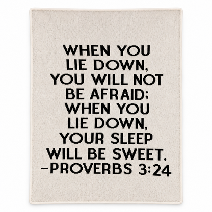 Natural ivory Proverbs 3:24 recycled cotton blanket with black block lettering, shown flat with smooth finished edges on white.