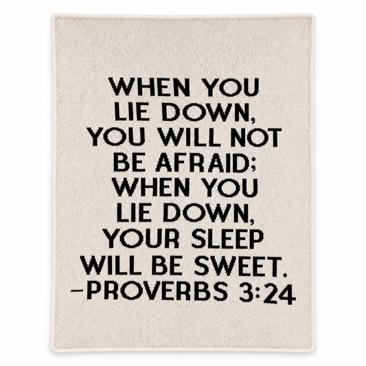 Natural ivory Proverbs 3:24 recycled cotton blanket with black block lettering, shown flat with smooth finished edges on white.
