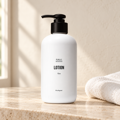 Public Goods 12 oz lotion bottle with black pump on a stone vanity beside a white towel.