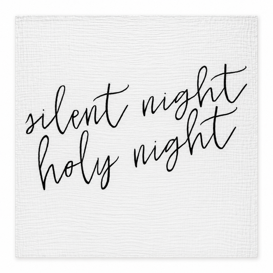 Silent Night Holy Night white muslin swaddle laid fully open on white, showing black hand lettering and stitched square edges.