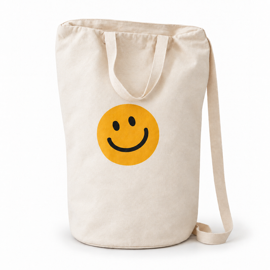 Smiley Face ivory cotton canvas bag with yellow smile, carrying handles and shoulder strap on white