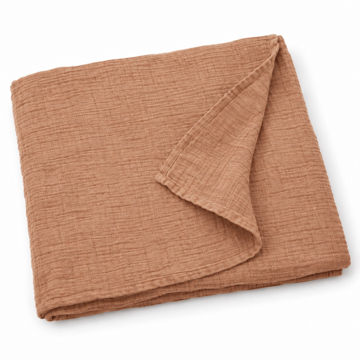 Ginger organic cotton muslin swaddle folded on white, with a turned corner showing the fine weave and hem.