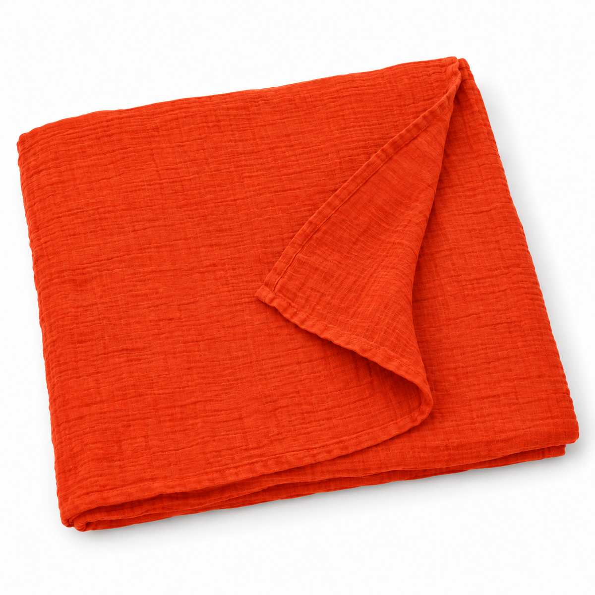 Wildfire orange organic cotton muslin swaddle folded on white, with a turned corner showing the fine weave and hem.