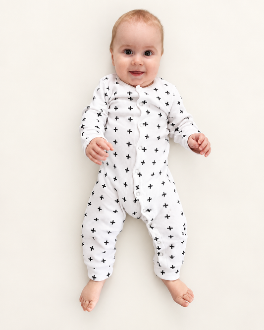 Baby wearing white Swiss Cross thermal coverall with front snaps and bare feet