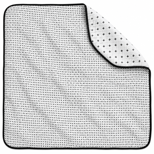 Swiss Cross + XO Reversible Muslin Quilt — one quilt with a folded corner showing both reversible prints.