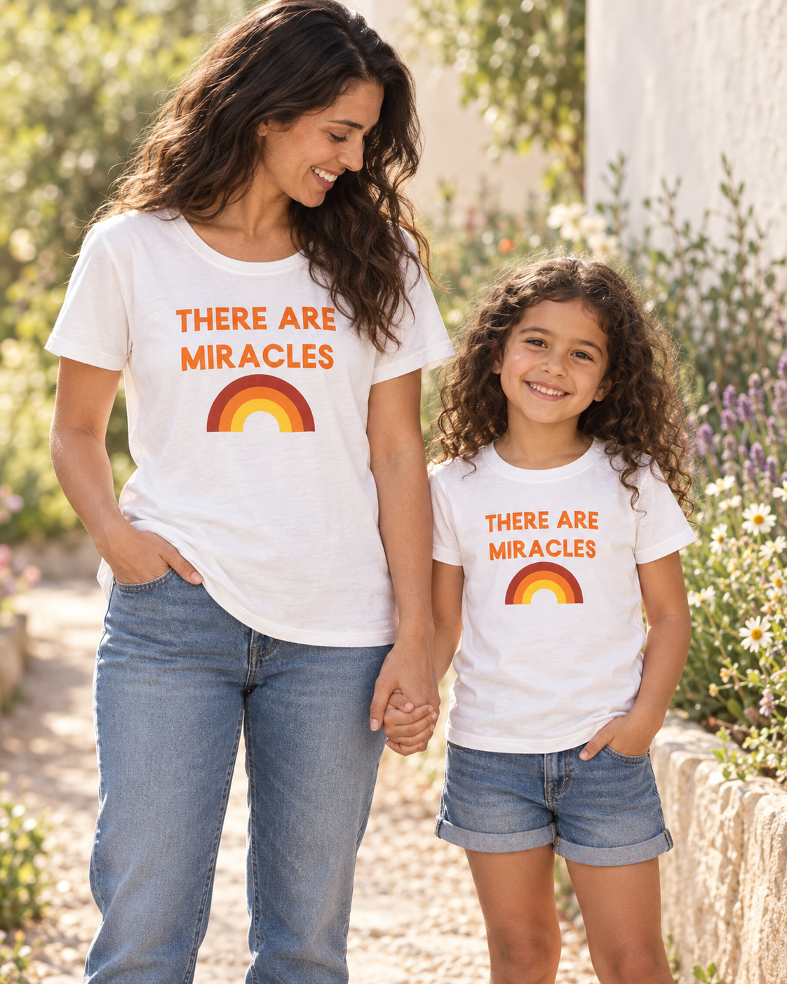 AI-styled mother and daughter wearing matching There Are Miracles tees outdoors; each tee sold separately