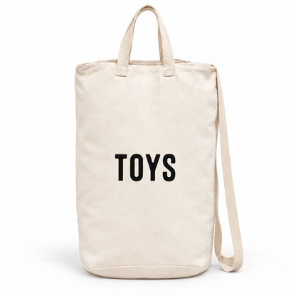 Toys ivory cotton canvas bag with black lettering, handles and shoulder strap on white