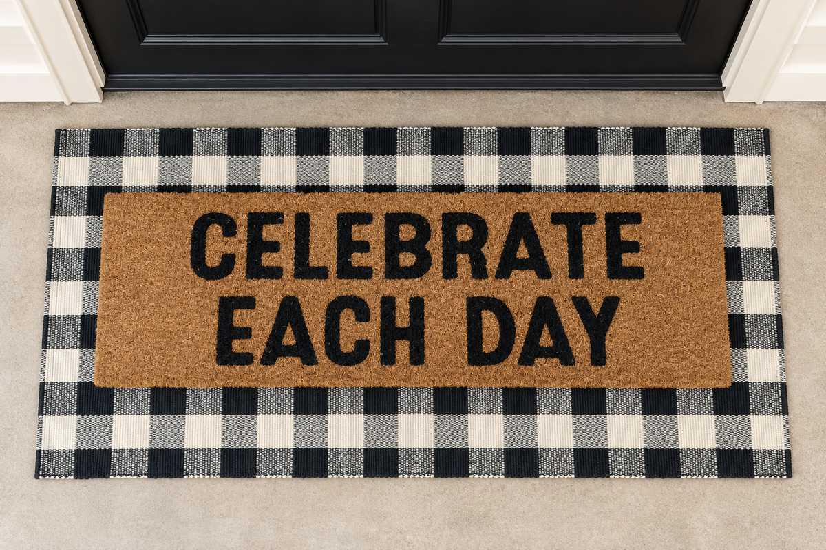 XL Doormat | Celebrate Each Day layered over a black and ivory buffalo plaid runner at a black door.