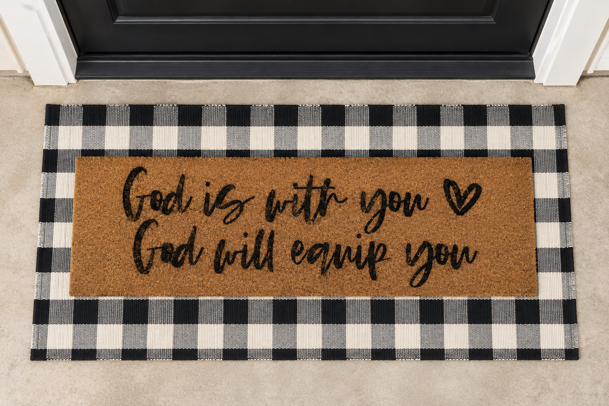 XL Christian Doormat | God Is With You, God Will Equip You layered over a black and ivory buffalo plaid runner at a black door.
