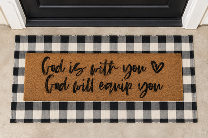 XL Christian Doormat | God Is With You, God Will Equip You layered over a black and ivory buffalo plaid runner at a black door.