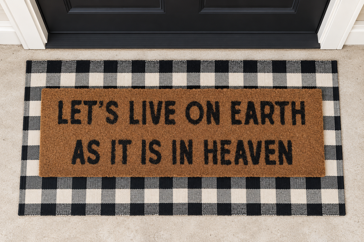 XL Doormat | Let's Live on Earth as It Is in Heaven layered over a black and ivory buffalo plaid runner at a black door.